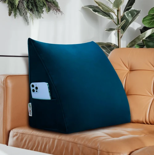 Granatowa poduszka wspierająca plecy, widoczna na tle eleganckiej, karmelowej sofy skórzanej.