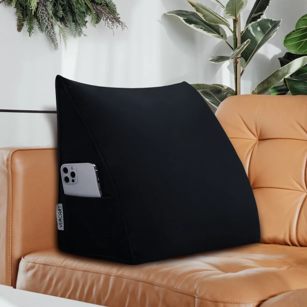 Czarna poduszka wspierająca plecy, widoczna na tle eleganckiej, karmelowej sofy skórzanej.