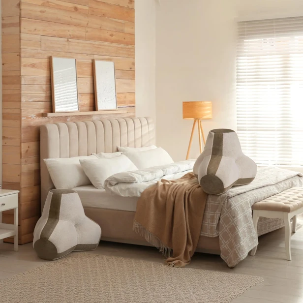 Aranżacja sypialni w neutralnych, ciepłych kolorach, gdzie centralnym elementem są dwie duże, geometryczne poduszki do siedzenia/oparcie