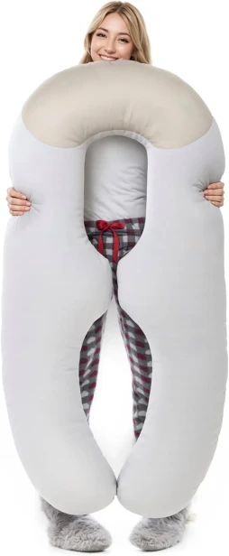 Młoda kobieta trzymająca dużą, profilowaną poduszkę ciążową w kształcie litery U. Biała