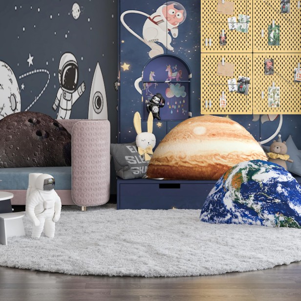 Komplet poduszek planet: Jowisz, Ziemia i Księżyc w granatowym pokoju dziecięcym z żółtymi szafkami i kosmiczną tapetą.