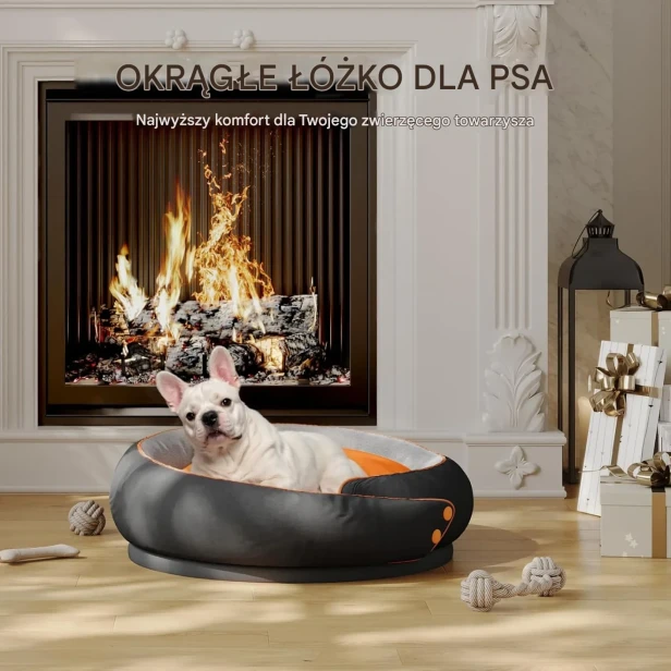 Biały buldog francuski leży w luksusowym, okrągłym legowisku w kolorze czarno-pomarańczowym przed palącym się kominkiem.