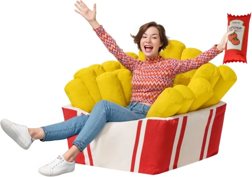 Duży, zabawny fotel worek sako w kształcie kartonu frytek z żółtymi frytkami, na którym siedzi uśmiechnięta kobieta, trzymająca pluszowy keczup.