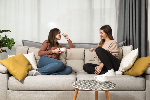 Dwie kobiety opierające się na kanapie o Poduszkę Zagłówkową ze Schowkiem Beżowo-Szara