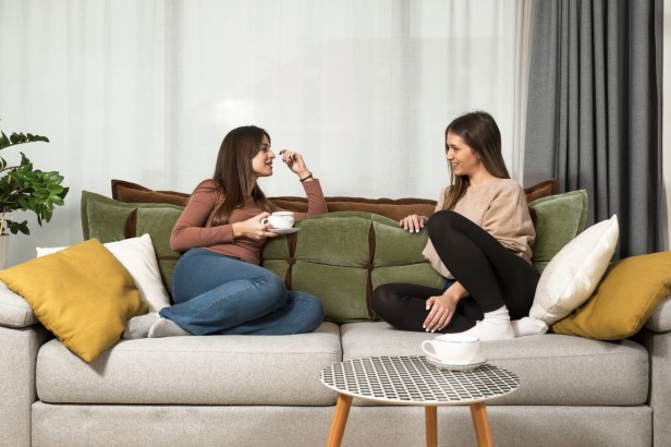 Kobiety opierające się na kanapie o Poduszkę Zagłówkową ze Schowkiem Zielono-Pomarańczowa