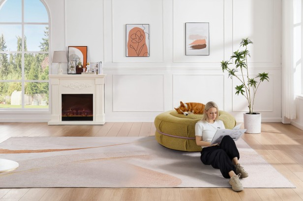 Kobieta opierająca się w salonie o Pufę Makaronik Zieloną na której leży pies.