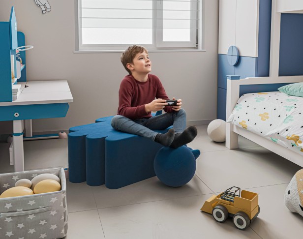 Chłopiec siedzący i grający na Nowoczesnej Niebieskiej Pufie.