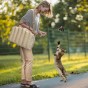 Kobieta bawiąca się z kotem w parku z luksusową torbą dla zwierząt na ramieniu.