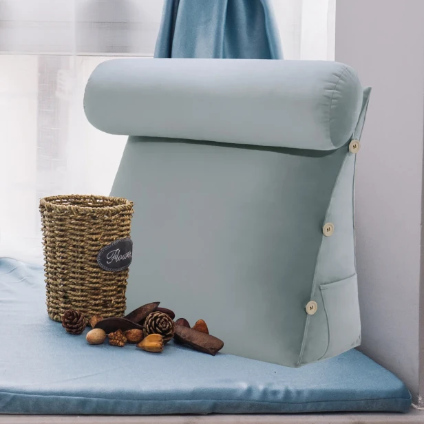 Modułowy Zagłówek z Wałkiem – Szary Welur umieszczony w przytulnym, zaaranżowanym miejscu do siedzenia przy oknie, idealnym do czytania.