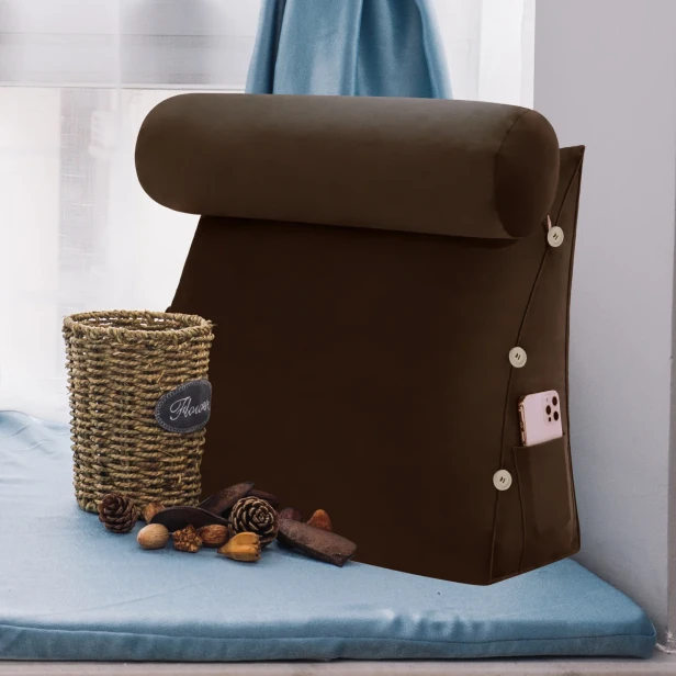 Modułowy Zagłówek z Wałkiem – Brązowy Welur umieszczony w przytulnym, zaaranżowanym miejscu do siedzenia przy oknie, idealnym do czytania.