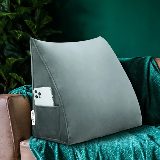 Szara poduszka wspierająca plecy, widoczna na tle kanapie w salonie.